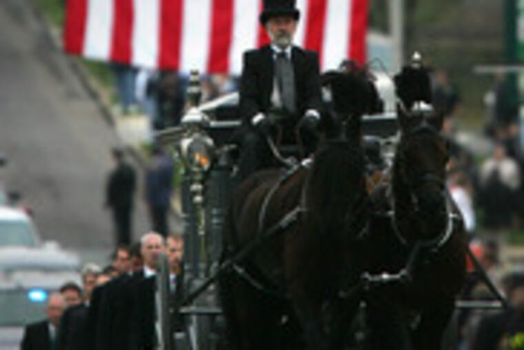 A horse-drawn carriage takes the casket to Highland Memorial Park in Pottstown. Barry Lee Bush, of Easton, Pa., was born in Pottstown and once served on its police force.