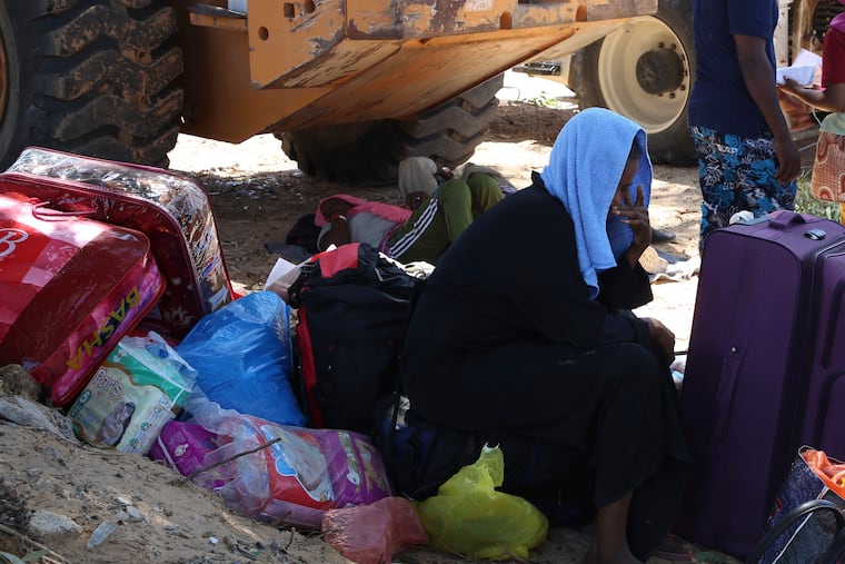 A migrant sits with his belongings as debris covers the ground after an airstrike at a detention center in Tajoura, east of Tripoli in Libya, Wednesday, July 3, 2019. An airstrike hit the detention center for migrants early Wednesday, killing several.