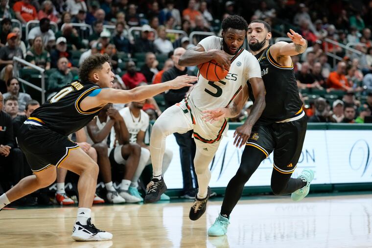 Miami guard Wooga Poplar (5) pushes through the defense of La Salle guard Andres Marrero (0) and La Salle guard Daeshon Shepherd during their game on Saturday.
