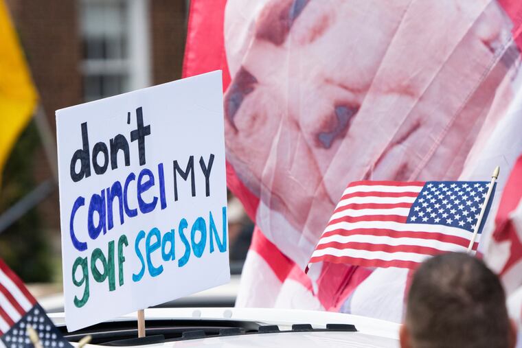 A sign demanding Gov. Tim Walz not to ban people from golfing is held through a sunroof during a "Liberate Minnesota" protest in St. Paul, Minn., on April 17.