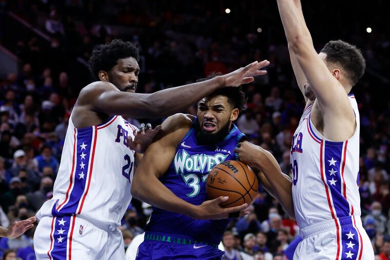 Minnesota Timberwolves center Karl-Anthony Towns drives to the basket defended by Sixers center Joel Embiid and forward Georges Niang.