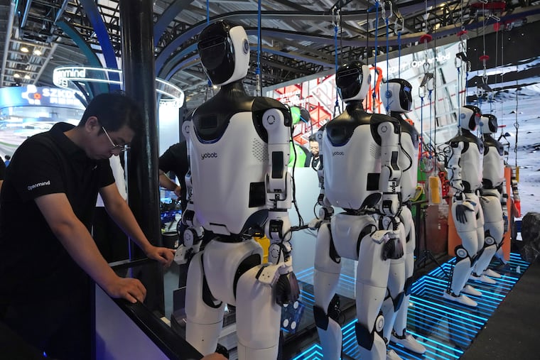 FILE - A worker reacts near a line of humanoid robots displayed at the World AI Conference in Shanghai, Friday, July 17, 2026.