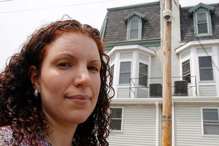 Michelle Perez, standing behind her house, shows a surveillance camera on a pole. ( AKIRA SUWA / Staff Photographer )