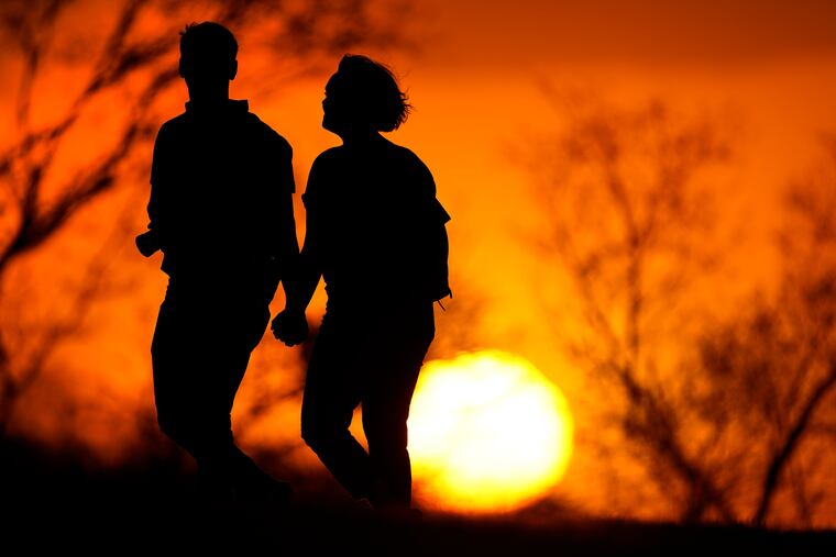 A couple walks through a park at sunset in 2021 in Kansas City, Mo.