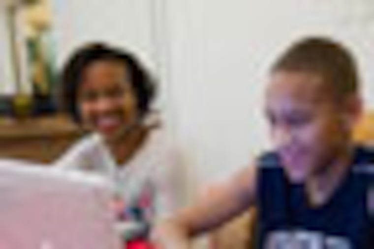 Jamil Pines-Elliott (left) works on African history studies, while his twin brother Jalil works on French homework on a laptop, and their mother, Moneek Pines-Elliott sits with them at the the dining room table of their home, December 14, 2011. ( David M Warren / Staff Photographer ) EDITORS NOTE: MG1WORK03 126212 PHILADELPHIA 121411 In the last year, several high-profile school districts have revised their homework policies (Lower Merion is one of those) in an effort to scale back some of the intensity and pressures on kids. Meantime, at Masterman, an 8th-grade teacher sees her kids nodding off from exhaustion after staying up late to do homework, and parents of middle- and high-school kids at both public and private schools say. Photos taken of Jamil and Jalil, and their mother, Moneek Pines-Elliott in their home.