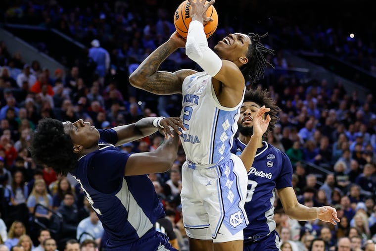 Saint Peter's forward Clarence Rupert (left) falls back after taking an elbow from North Carolina guard Caleb Love during the first half in the East Regional Finals on Sunday, March 27, 2022.