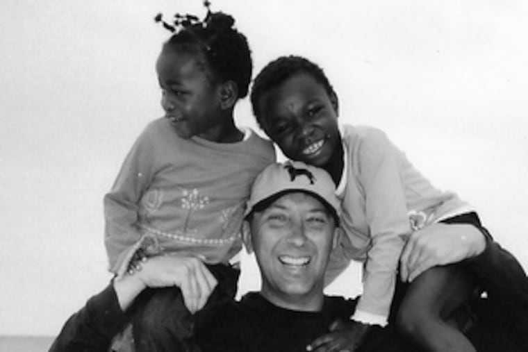 Steven J. Kameika carries Effy (left) and Fudia, war orphans he adopted. For a time, he taught at-risk students in New York.