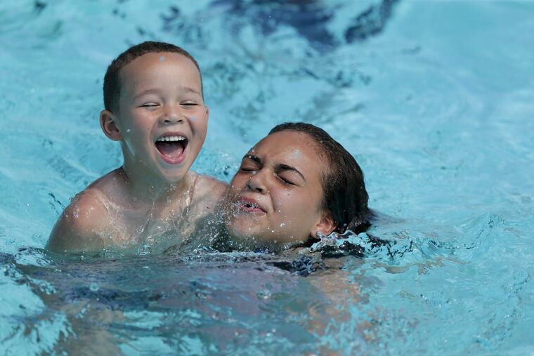 Ariana Glenn, 14, helps his brother Tristan Barnes, 7, swim during the official opening of public pools for the 2018 summer season at the Lawncrest Pool in Philadelphia, PA on June 19, 2018.