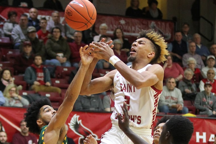 Jaire Grayer, left, of George Mason stripping the ball away from Charlie Brown, center, of St. Joseph’s during the first half last week.