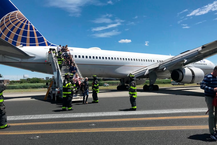 This photo provided by Caroline Craddock shows emergency personnel help passengers off a plane after a United Airlines plane skidded off the runway after landing at Newark Liberty International Airport on Saturday, June 15, 2019 in Newark, N.J. (Caroline Craddock via AP)