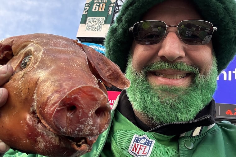 Jeremy Smith, a chef who lives in Port Richmond, poses with the head of the pig he cooked at the NFC Championship game on Sunday outside Lincoln Financial Field.