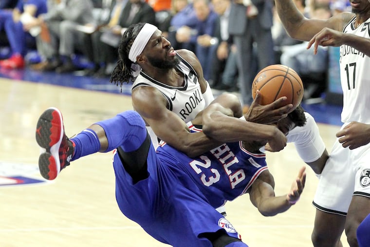 Jimmy Butler, bottom, of the Sixers gets roughly fouled by DeMarre Carroll of the Nets during the 1st half of their NBA playoff game at the Wells Fargo Center on April 13, 2019.