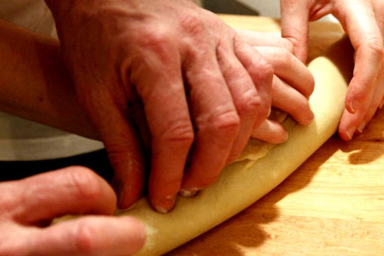 The hands of tradition: Jim and Kelsey Bezila work together on a delicious treat and a piece of history, past and future.
