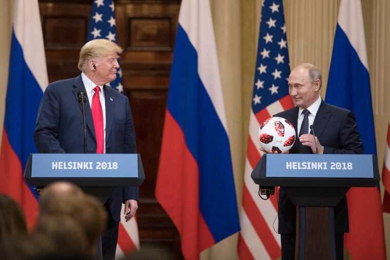 President Donald Trump smiles while Vladimir Putin, Russia's president, holds a soccer ball during a news conference in Helsinki, Finland, on July 16, 2018.