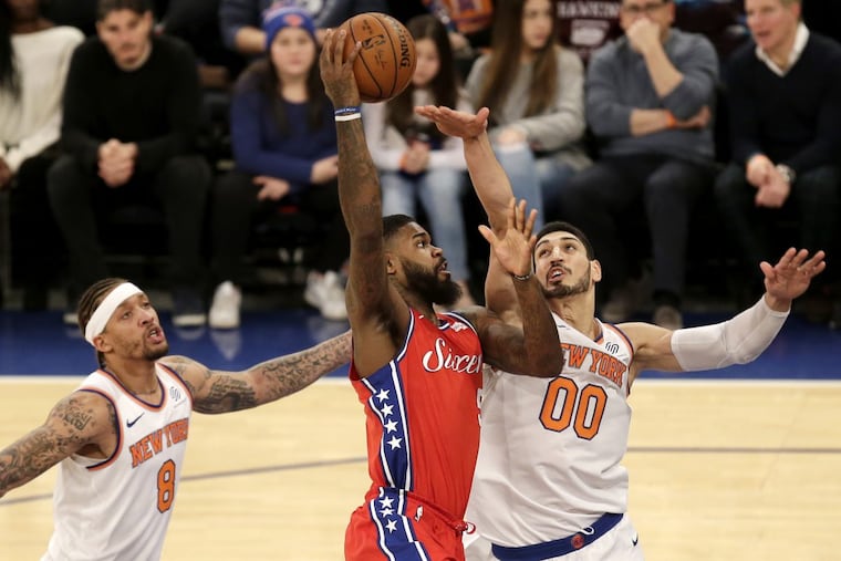 The Sixers’ Amir Johnson, center, drives to the basket past New York Knicks Enes Kanter, right, and Michael Beasley during the first half.
