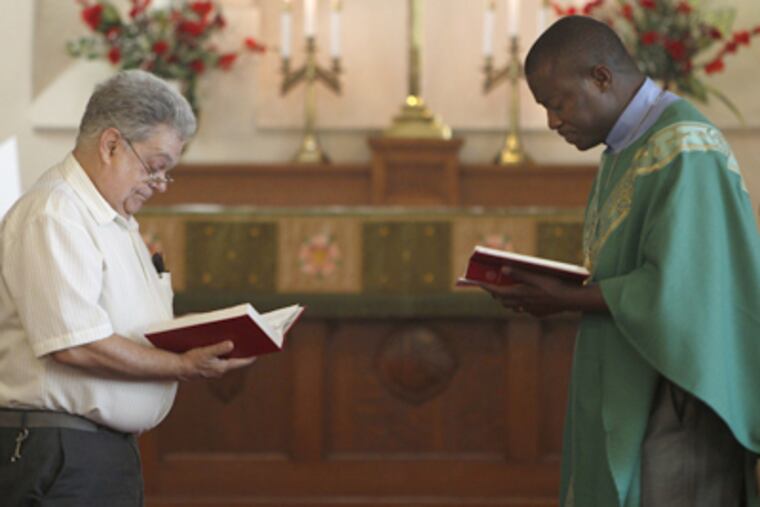At the 9:30 a.m. service at Faith Immanuel, member Frank Miller (left) and Pastor Moses Suah-Dennis pause before a reading. (David Maialetti / Staff Photographer)
