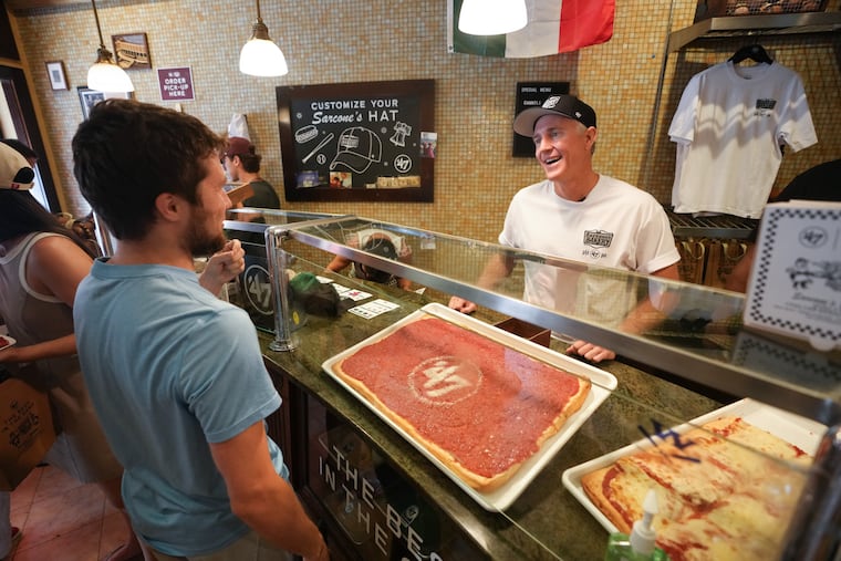 Chase Utley interacts with Jeremy Otten at Sarconnes Bakery, where the bakery and the official MLB licensee for headwear and apparel, hosted Utley to sign autographs and meet fans, in Philadelphia, July 13, 2026.