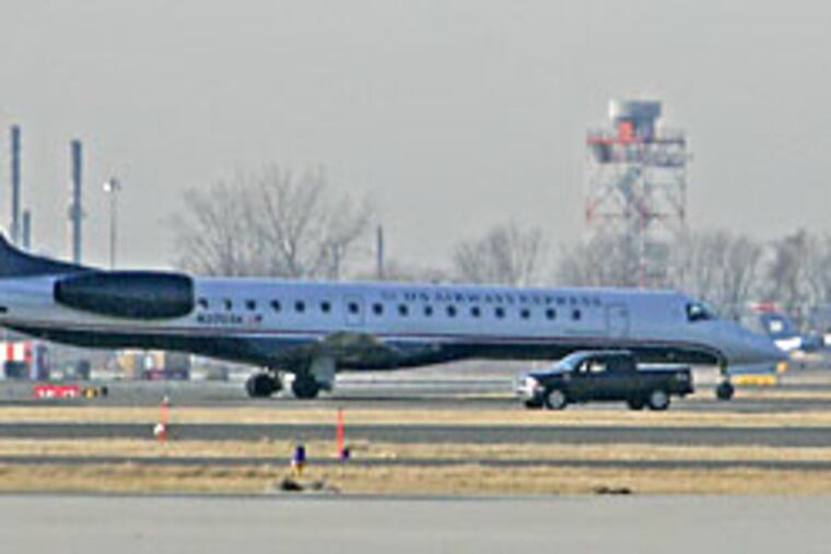 A US Airways Express jet sits on the tarmac at Philadelphia International airport surrounded by police and emergency vehicles, far from the gates, after taking a male passenger off the airplane.