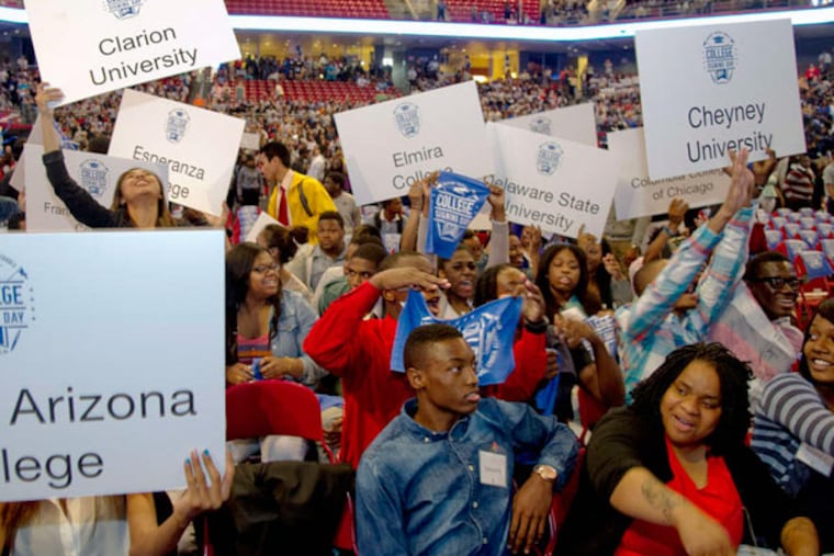 Graduating seniors from Mastery Charter Schools wave signs with the names of the colleges they will attend. The seniors joined thousands of underclassmen at Temple University's Liacouras Center. (Clem Murray / Staff Photographer)