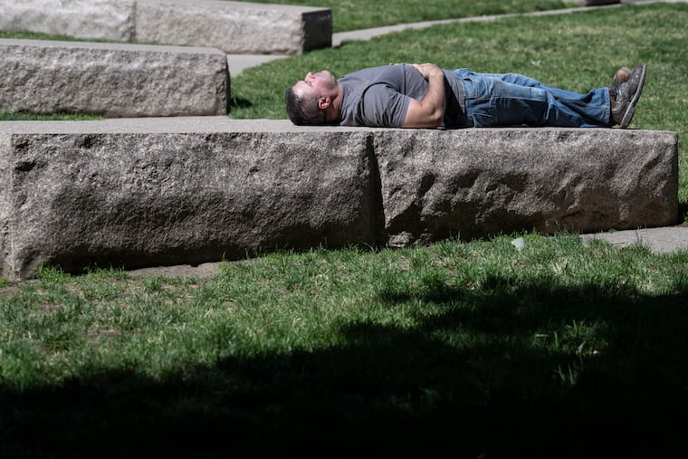 Steve Cappella basks in the sun atop large stones at Lubert Plaza in Philly earlier this month. He might prefer air-conditioning the next few days.
