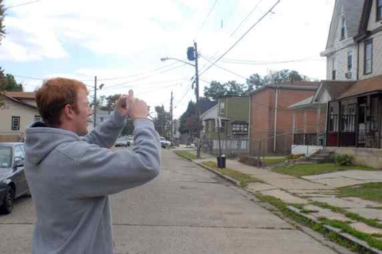 Shawn Murray, a Rowan University student, takes photos in Cramer Hill to be used in a computer model of the neighborhood's storm-water woes.