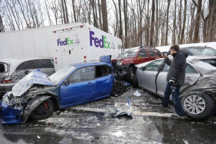 A man inspects vehicles piled up in an accident, Friday, Feb. 14, 2014, in Lower Southampton. Traffic accidents involving multiple tractor trailers and dozens of cars completely blocked one side of the Pennsylvania Turnpike outside Philadelphia for several hours and caused some injuries. (AP Photo/Matt Rourke)