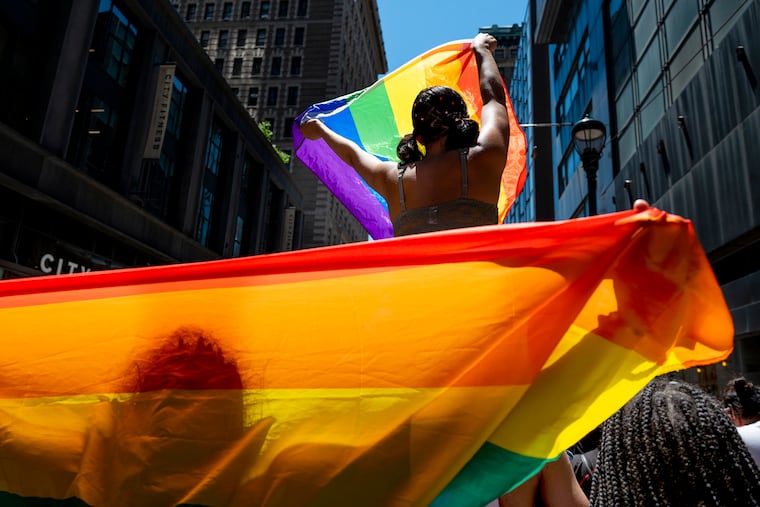 Marchers carry flags heading down 13th Street toward the Pride festival in the Gayborhood with entertainment, food, and games in the city's 50th annual Pride celebration.