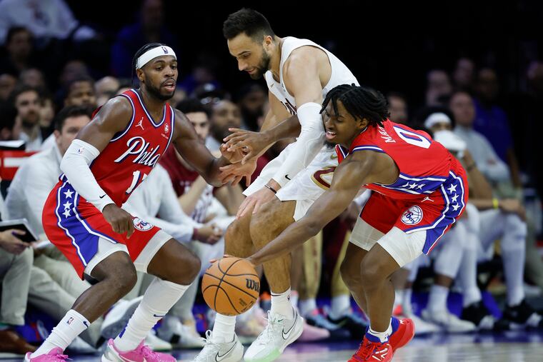 Sixers guard Tyrese Maxey gets fouled by Cleveland Cavaliers guard Max Strus while going for a loose ball with teammate Buddy Hield.