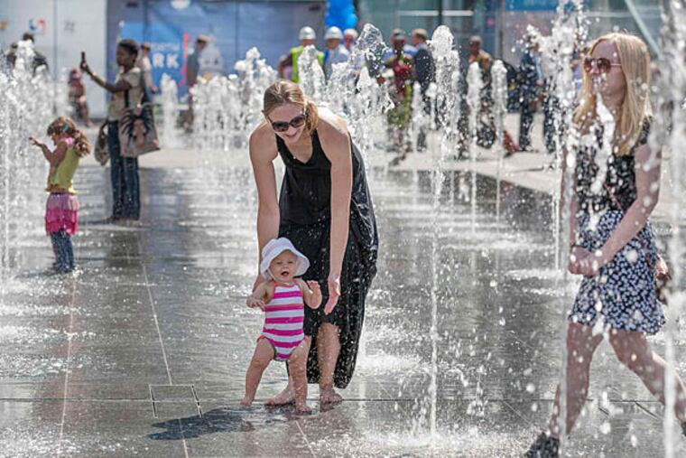 With a guiding hand from mother Melissa, Avery Vadnais navigates the fountains on Thursday at the newly opened Dilworth Park. One-third of the park is unfinished, due to be completed by Thanksgiving.