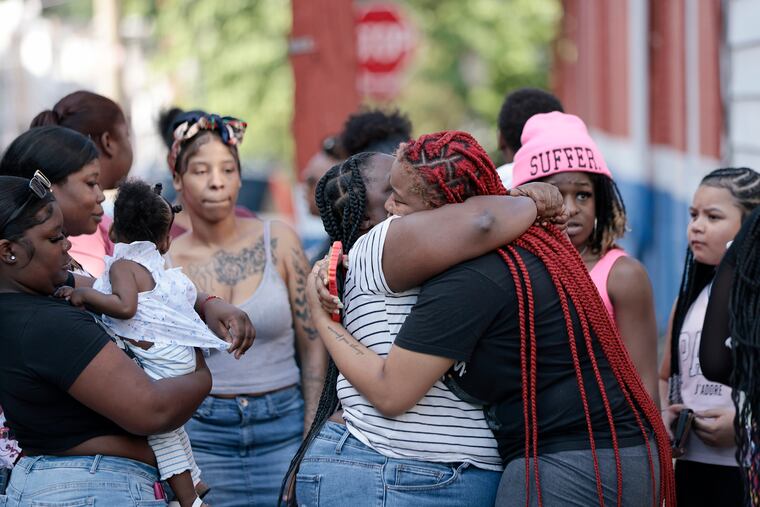 Surrounded by friends and family, Robin Harmon (striped shirt) is hugged after a vigil for her son Ernie Harmon-Tague in front of her home in Philadelphia on Saturday. Ernie, 9, drowned on Monday while playing in a creek.
