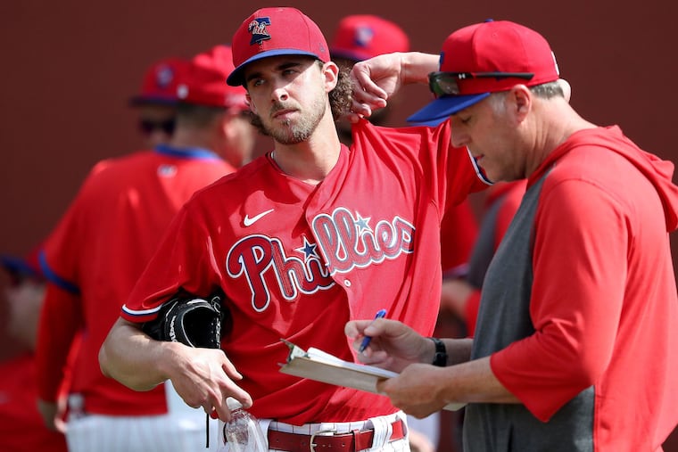 Philadelphia Phillies ace Aaron Nola talks with pitching coach Bryan Price, right, after throwing a bullpen session last week.
