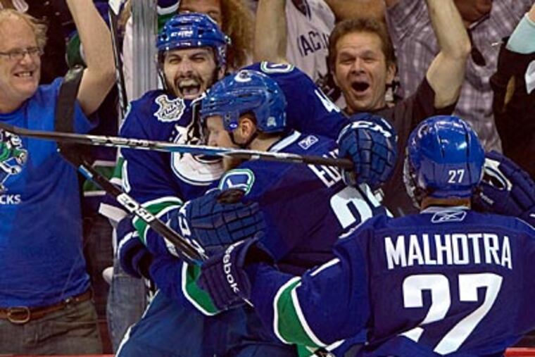 Maxim Lapierre celebrates with Alexander Edler and Manny Malhotra during Game 5. (AP Photo/The Canadian Press, Darryl Dyck)