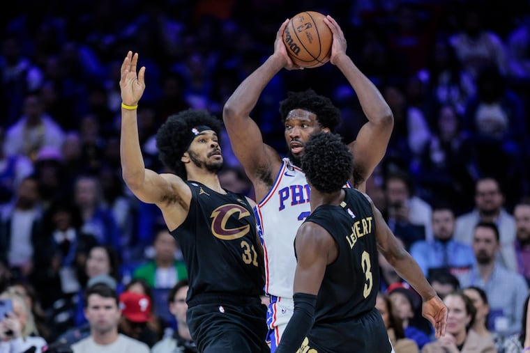 Sixers center Joel Embiid looks to pass between Cavaliers Jarrett Allen (left) and Caris LeVert on Wednesday.