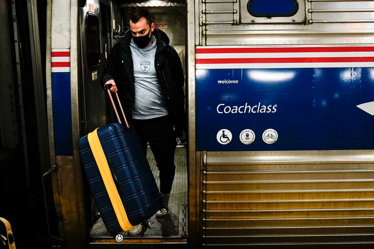 FILE - A traveler exits an Amtrak train ahead of the Thanksgiving Day holiday at 30th Street Station in Philadelphia, Wednesday, Nov. 24, 2021. Amtrak will need to reduce service in January unless more employees get vaccinated against COVID-19, the passenger rail system’s president says. Stephen Gardner says about 95% of Amtrak workers are at least partially vaccinated. The rest face a Jan. 4 deadline that the Biden administration set for employees of federal contractors. (AP Photo/Matt Rourke, File)
