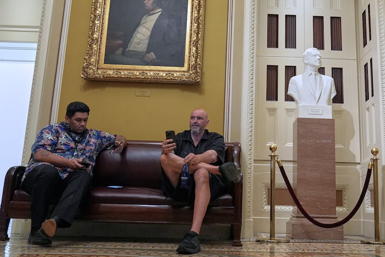 Sen. John Fetterman, D-Pa., right, sits and holds his mobile phone at the U.S. Capitol Tuesday, July 1, 2025, in Washington. (AP Photo/Mariam Zuhaib)