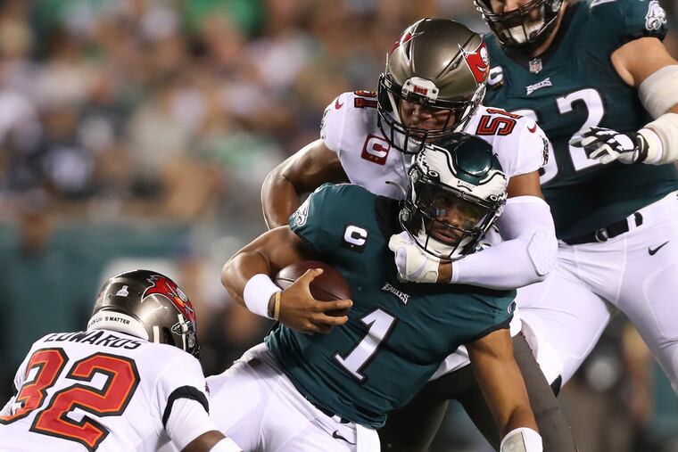 Eagles quarterback Jalen Hurts gets taken down against Tampa Bay Buccaneers safety Mike Edwards and linebacker Kevin Minter (right) during the first quarter on Thursday, October 14, 2021 in Philadelphia.