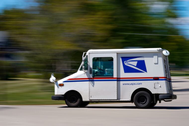 A mail truck moves down a street in Fox Point, Wis.