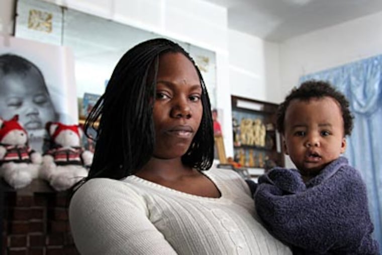 Anthoinette Medley with her 14-month-old son, Timir, and a photo of Timir’s twin brother, Nelsir, who died in an Infantino SlingRider. Yesterday, the firm agreed to recall about a million of the devices. (LAURENCE KESTERSON / Staff Photographer)