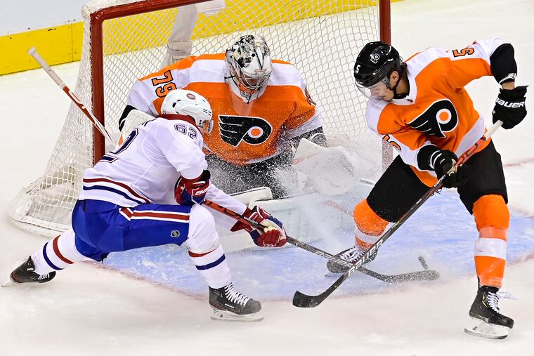 Flyers goaltender Carter Hart makes a save on Montreal's Artturi Lehkonen (left) as Phil Myers defends in Game 1 of the Eastern Conference quarterfinals.