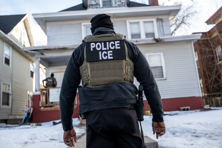 An Immigration and Customs Enforcement agent stands outside a home during a raid in south Minneapolis on Jan. 13.