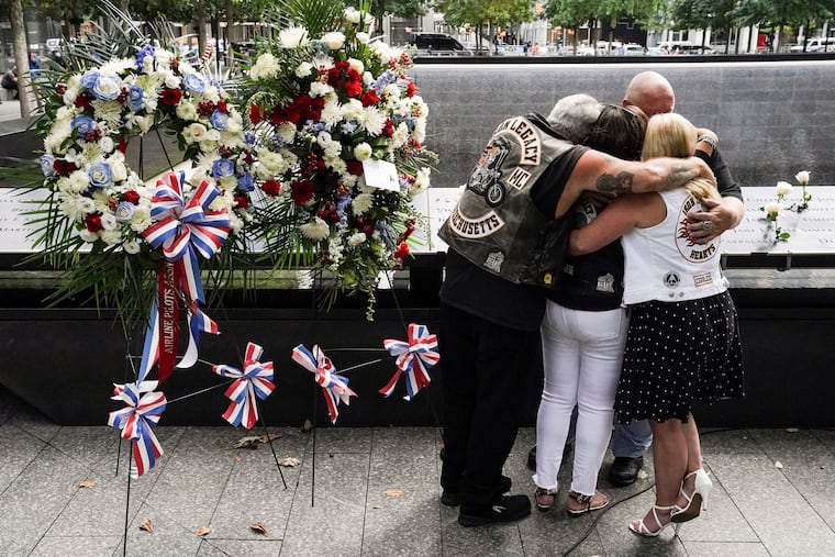 Mourners hug beside the names of the deceased Jesus Sanchez and Marianne MacFarlane at the National September 11 Memorial and Museum, Friday, Sept. 11, 2020, in New York. Americans commemorated 9/11 with tributes that have been altered by coronavirus precautions and woven into the presidential campaign.