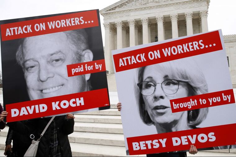 Members of the American Federation of Teachers hold up signs depicting Education Secretary Betsy DeVos and Koch Brother, David Koch, while protesting in support of unions outside of the Supreme Court, Monday, Feb. 26, 2018, in Washington. The Supreme Court takes up a challenge in a case that could deal a painful financial blow to organized labor. The court is considering a challenge to an Illinois law that allows unions representing government employees to collect fees from workers who choose not to join.