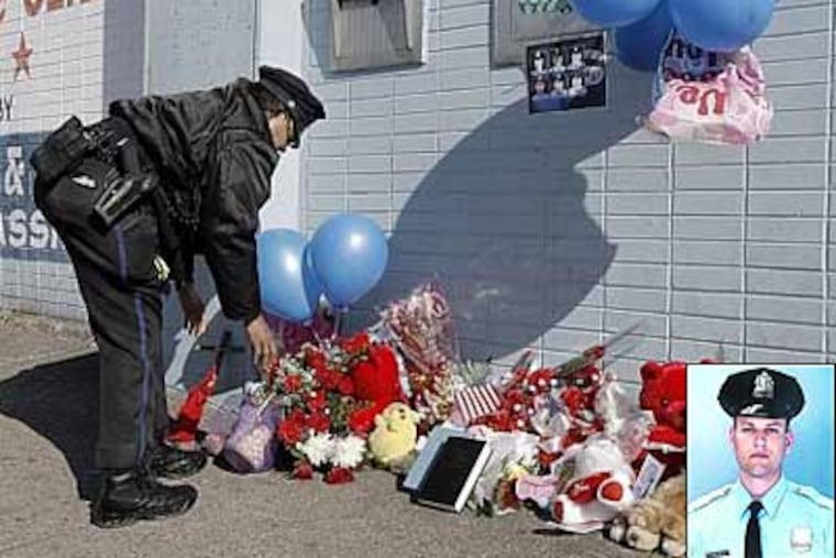 35th District police officer Nannette Taylor fixes a memorial on Sunday to fellow officer John Pawlowski, at Broad and Olney streets near where he was slain. (Akira Suwa / Staff Photographer ).