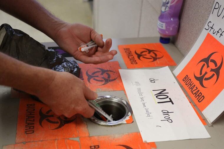 A drug user drops a series of used syringes into a wastebasket.