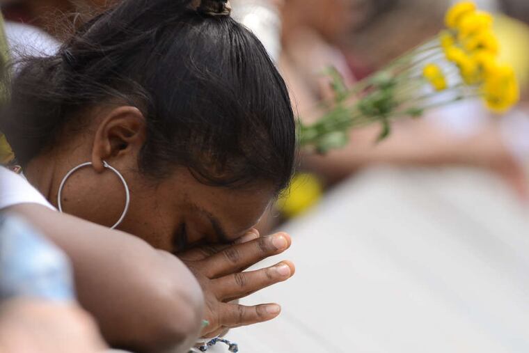 Prayers and hope: At the ritual offering of fruit and flowers to Yoruba goddess Oshun, dropped from the South Street Bridge into the Schuylkill to begin the Odunde festival, a participant makes a supplication.