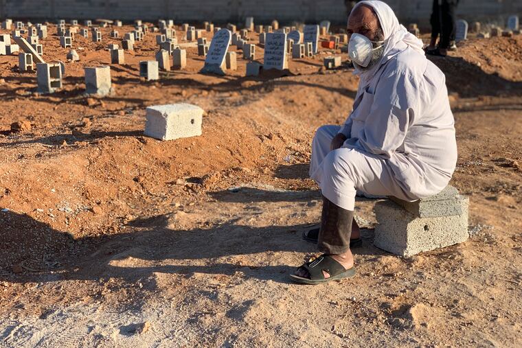 A man sits by the graves of the flash flood victims in Derna, Libya, Friday, Sept. 15, 2023. The death toll in Libya's coastal city of Derna has soared to over ten thousand as search efforts continue following a massive flood fed by the breaching of two dams in heavy rains, the Libyan Red Crescent said Thursday. (AP Photo/Yousef Murad)