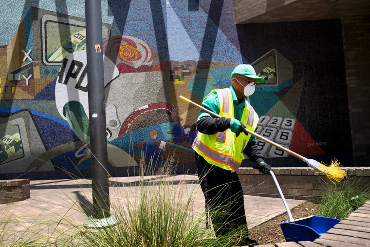 A cleaning crew sweeps up in front of LAPD Central Community Police Station in downtown Los Angeles on Thursday, May 30, 2019. The union that represents the LAPD is demanding a cleanup of homeless encampments in the city after one detective who works downtown was diagnosed with typhoid fever and two others are showing similar symptoms.