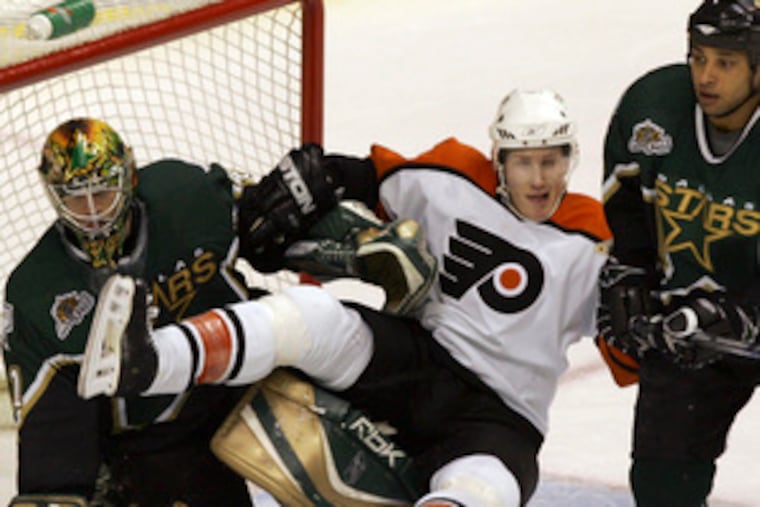 Dallas goalie Mike Smith dumps Joni Pitkanen with Trevor Daley in close range. Later, the Stars' Mike Modano tallied his 500th goal.