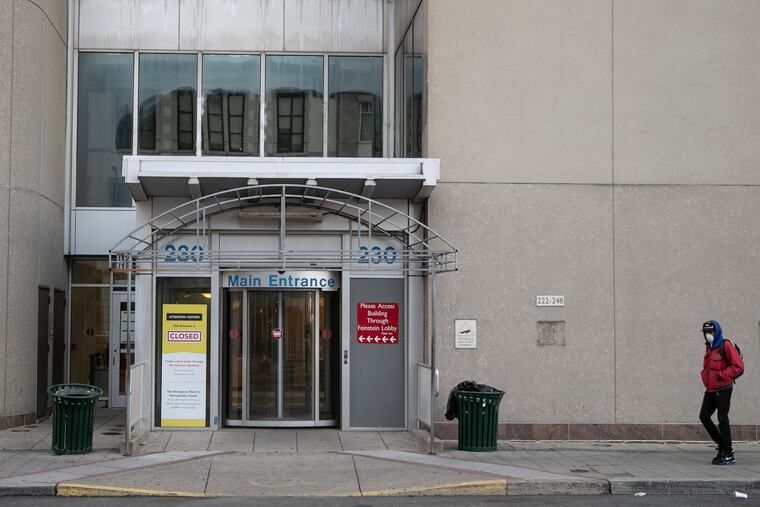 A pedestrian in a mask walks by the closed Main Entrance of Hahnemann Hospital on Tuesday, March 24, 2020. Mayor Jim Kenney accused the owner of the former Hahnemann University Hospital site on Tuesday of “trying to make a buck” out of the coronavirus pandemic by seeking a high rent for his building.