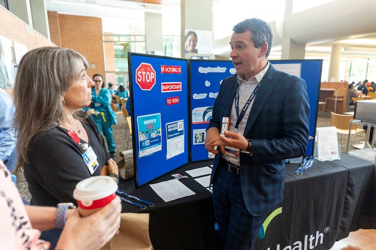 Lars Peterson, Lankenau's manager of patient experience, shows nurse Daria Salvitti the QR code that people can scan to register to vote at the hospital on Tuesday, Sept., 10, 2024.